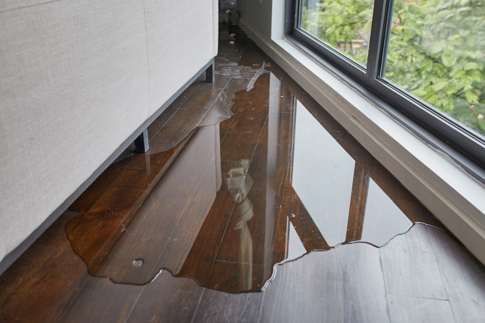 family room flooded with leak on hardwood floor behind couch
